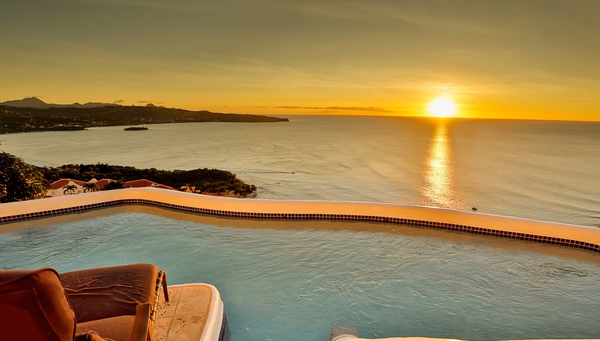A pool with a view of the ocean at sunset.