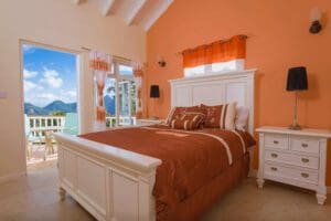 A bedroom with orange walls and white furniture.